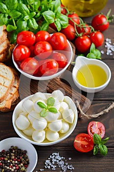 Italian food ingredients Ã¢â¬â mozzarella, tomatoes, basil and olive oil on rustic wooden table.